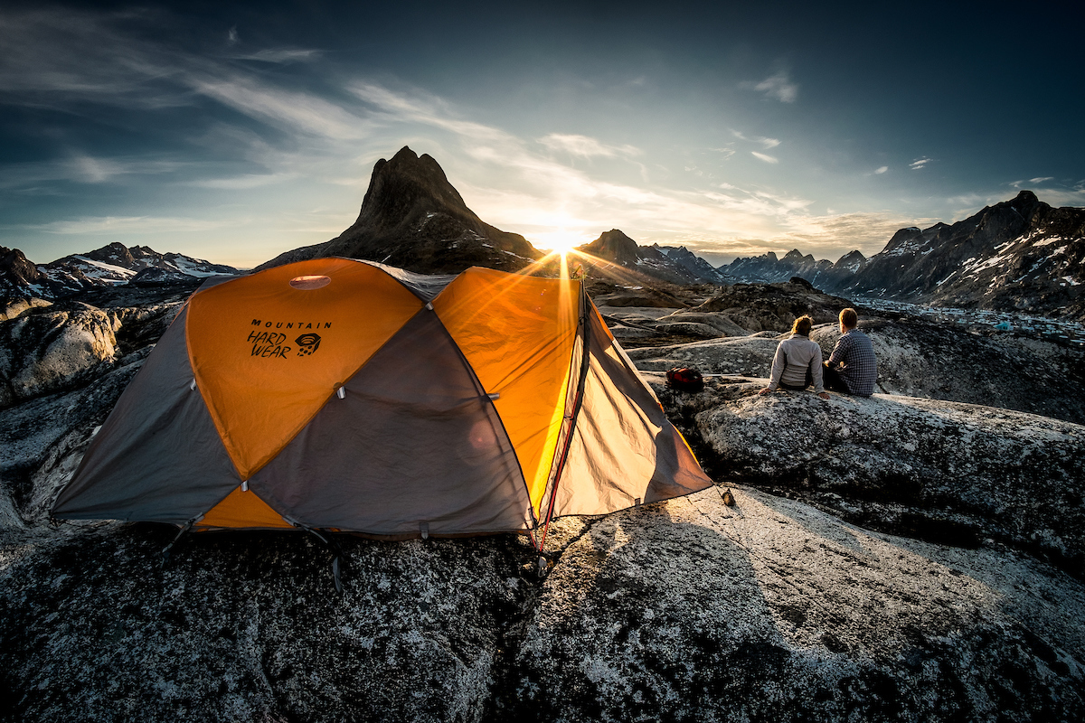 Sunset Over Two Hikers Near A Tent Camp At Qernertivartivit In East Greenland