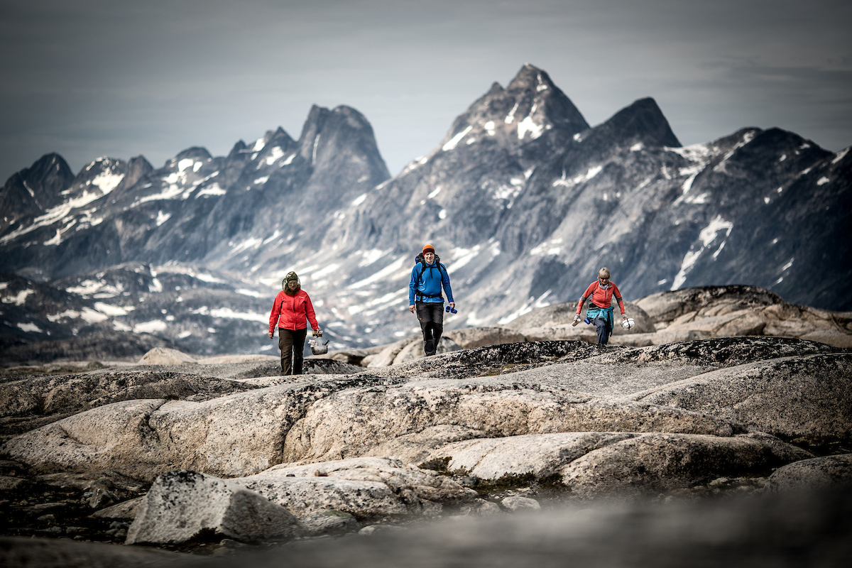 Three Hikers In The Mountains Near Qernertivartivit Not Far From Kulusuk In East Greenland
